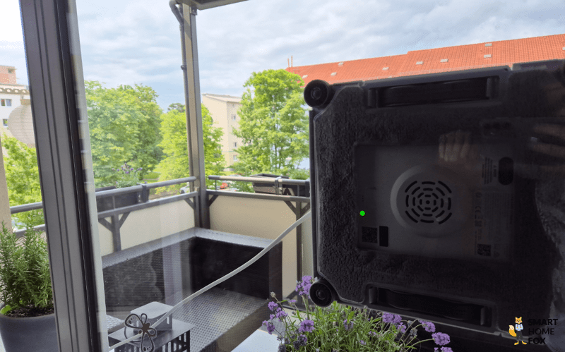 Der Dreame C1 Station Fensterputzroboter reinigt ein großes Wohnzimmerfenster.